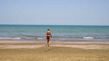 oldukça atletik kız modeli denizden, yavaş yavaş geliyor. Mavi mayolu,