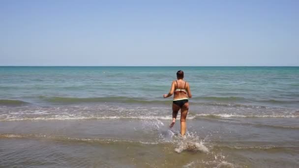 Pretty athletic girl model comes out of the sea, slowly. in a blue bathing suit, — Stock Video