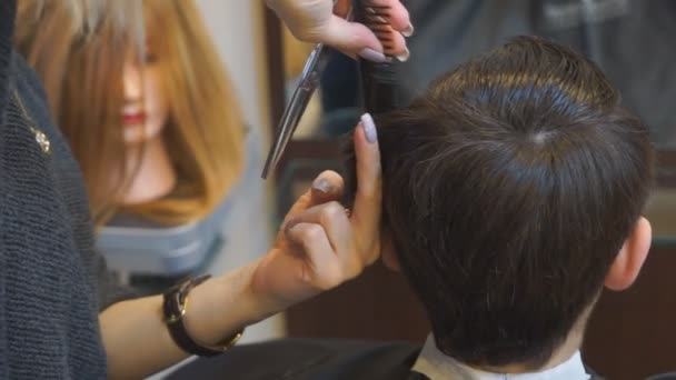 Un homme se fait couper les cheveux par un coiffeur. — Video