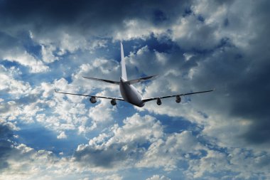 Gün batımında dramatik bulutların üzerinde uçan uçak