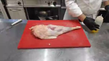 The chef in the restaurant prepares meat. Cooking dishes with boiled leg of lamb.