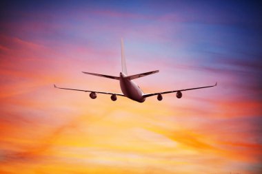 Airplane flying above dramatic clouds during sunset,sunrise.