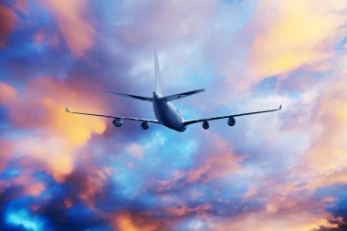 Airplane flying above dramatic clouds during sunset,sunrise.
