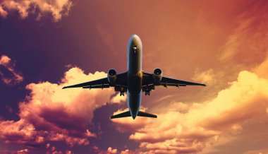 Airplane flying above dramatic clouds during sunset,sunrise.