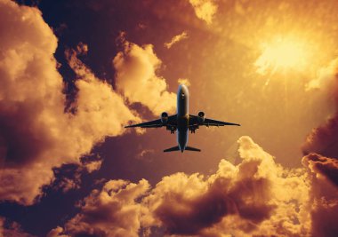 Airplane flying above dramatic clouds during sunset,sunrise.