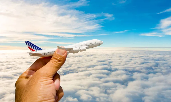 Ein Mann hält ein Modellflugzeug vor einem blauen Himmel mit weißen Wolken. — Stockfoto