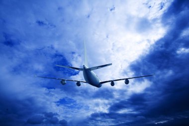 Airplane flying above dramatic clouds during sunset,sunrise.