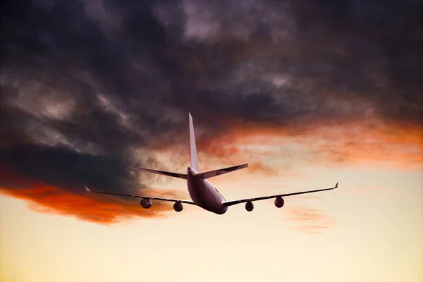 Flugzeug fliegt über dramatischen Wolken bei Sonnenuntergang, Sonnenaufgang. — Stockfoto