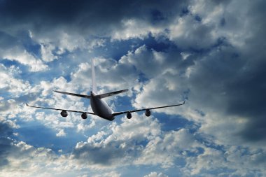 Airplane flying above dramatic clouds during sunset,sunrise.