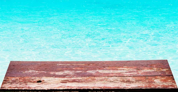 Brązowy drewniany stół przeciwko tropikalnej letniej plaży i fala morska przeciwko błękitnemu niebu. — Zdjęcie stockowe