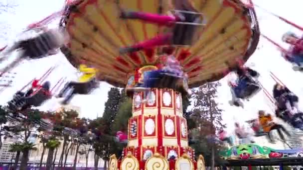 Gelukkige mensen rijden een draaimolen door de lucht in een stadspark — Stockvideo