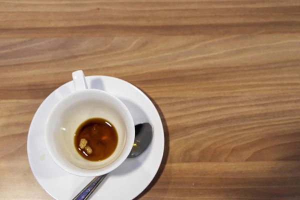 Een vieze witte koffiekop staat op een houten tafel. Restjes ontbijt. — Stockfoto