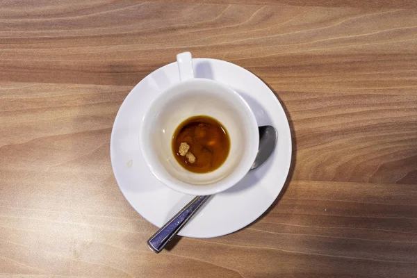 Una sucia taza de café blanco está en una mesa de madera. Desayuno a la izquierda. —  Fotos de Stock