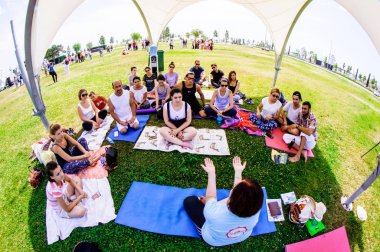 Bakü, Azerbaycan, 20 Mayıs 2019: Erkekler ve kadınlar yeşil bir açıklıkta bir parkta yoga yapıyorlar.