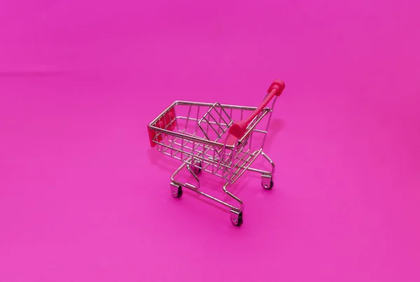 empty shopping cart on pink background. Shopping concept
