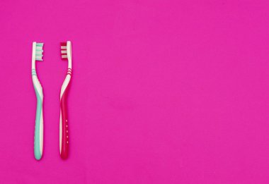 Kırmızı arka planda mavi ve kırmızı diş fırçası. Temizlik ve sağlık kavramı