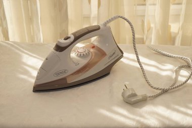 Bir pencere arkaplanına karşı ütü tahtasında beyaz ütü