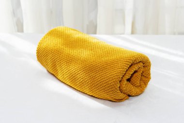 Beyaz bir masanın üzerindeki sarı havlu pencere arkaplanına karşı