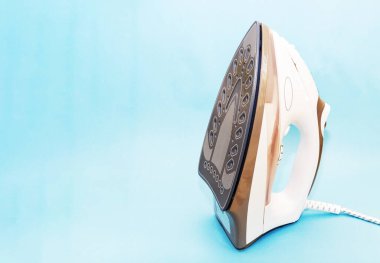 Mavi arka planda beyazlı modern buharlı elektrikli ütü.