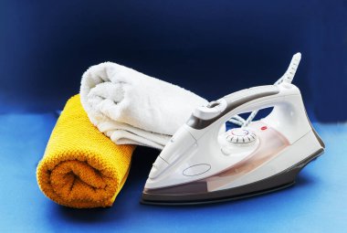 Koyu mavi arka planda çok renkli havlu ve beyaz ütü.