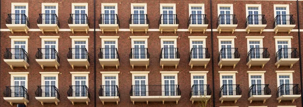 Vooraanzicht van een modern residentieel bruin bakstenen gebouw met balkons en ramen, close-up, patroon. — Stockfoto