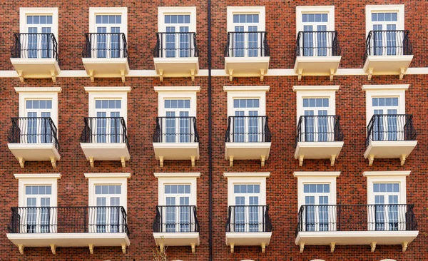 Vorderansicht eines modernen Wohngebäudes aus braunem Backstein mit Balkonen und Fenstern, Nahaufnahme, Muster. — Stockfoto