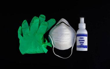 Virüs koruması. Tıbbi maske, dezenfektan jeli ve siyah arka planda laboratuvar eldivenleri. Coronavirus hastalığı COVID-19 salgını olabilir. Tıbbi solunum bandajı yüzü.