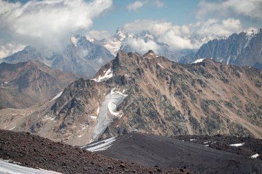 Elbrus yanardağı yakınlarındaki Kafkasya dağlarında buzullar, bulutlar ve tepeler.