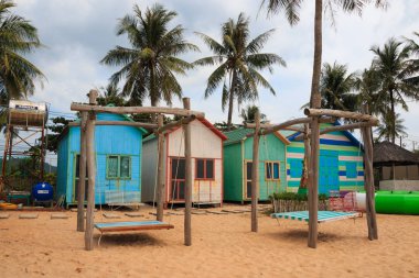 Duong Dong şehri, Phu Quoc, Vietnam - Aralık 2018: Palmiye ağaçlarının arasında sahilde küçük evler,