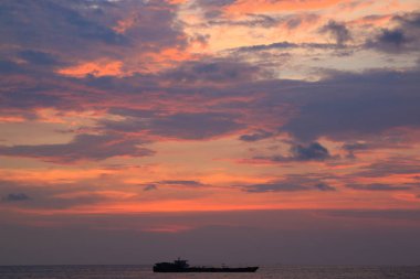 Gemiler, kayalar, ufuk çizgileri ve turuncu bulutlarla deniz kenarında resim gibi bir gün batımı. Phu Quoc, Vietnam.  