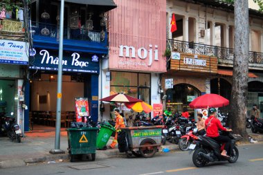 Ho Chi Minh şehri, Vietnam - Aralık 2018: Sokaktaki dükkan sırasının yakınındaki çöp konteynırları ve motosikletler.