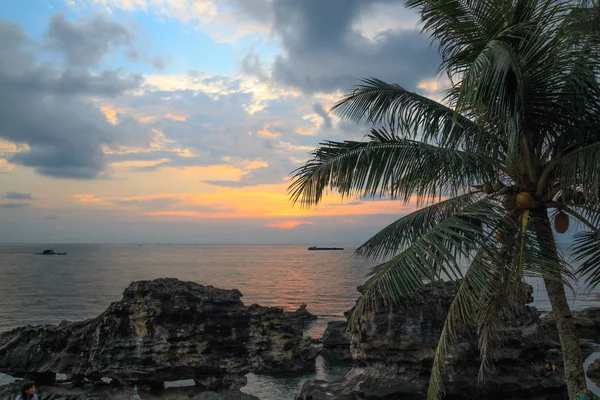 Hindistan cevizi palmiyesi, turuncu güneş, tekne ve bulutlu deniz kenarında gün batımı. Phu Quoc, Vietnam.  