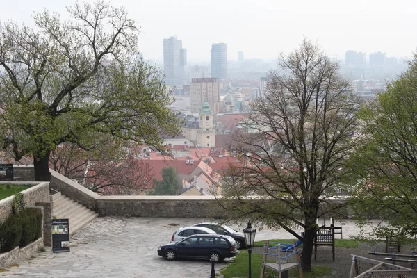 Bratislava, Slovakya - Nisan 2011: Bulutlu bir günde Bratislava Kalesi tepesinden ağaçlarla ve eski şehir manzaralı park.