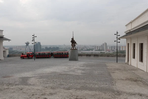Bratislava, Slovakya - Nisan 2011: Bratislava Kalesi 'nde bulutlu gökyüzü, Svatopluk anıtı ve küçük kırmızı eğlence treni.