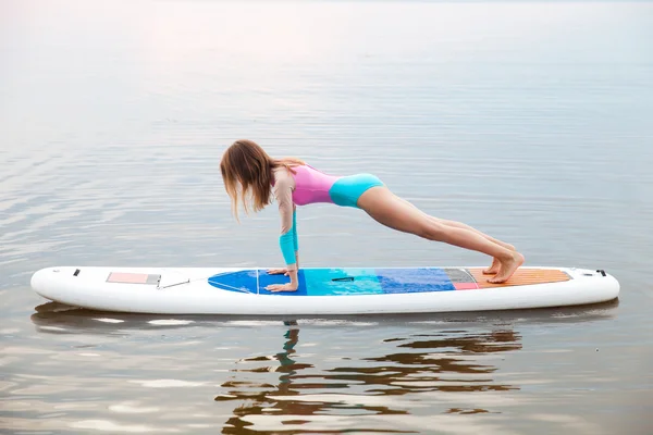 Frau macht Yoga auf Surfbrett mit Paddel — Stockfoto