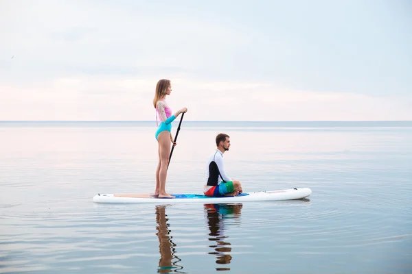 Junges Paar paddelt auf Surfbrett — Stockfoto