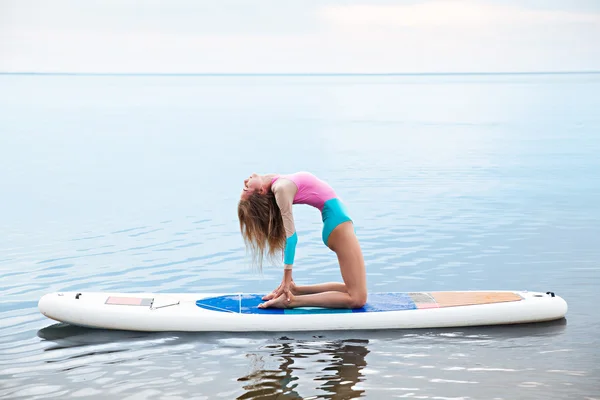 Woman doing yoga on sup board with paddle — Stock Photo, Image