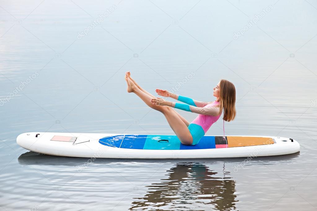 Woman doing yoga on sup board with paddle