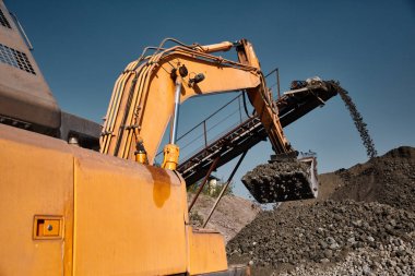 Kova ekskavatör sıcak bir açık havada cüruf dökümü çalışır. Arka planda çalışan konveyör bantlı ağır endüstriyel metalürjik sisli peyzaj