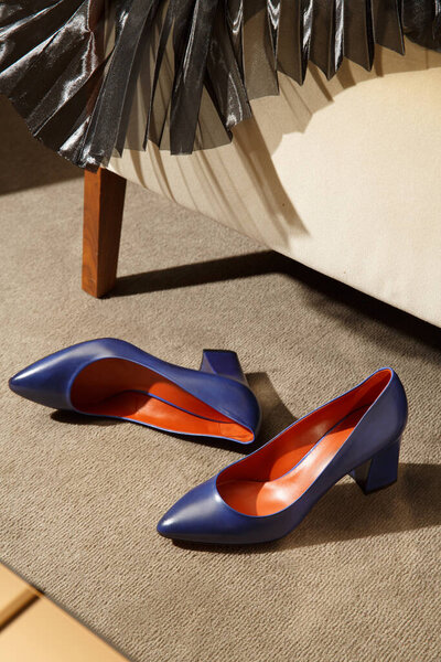 Custom made fashionable women's classic shoes and pleating skirt in minimalist luxury tailor studio apartment. Handcrafting, small business workshop concept. Closeup with copy space shopwindow image