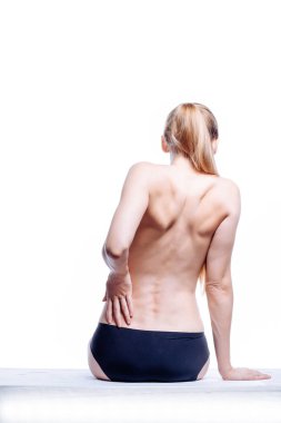 Güzel atletik kadın vücudu. Sırt ağrısı. Şortlu çıplak kadın. Beyaz arka planda izole edilmiş, arka planda stüdyo görüntüsü..