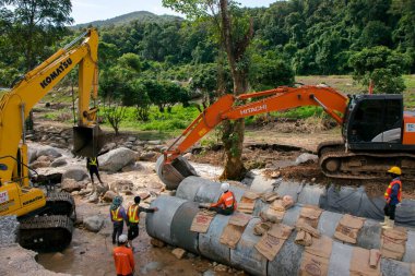 Chiangrai / Tayland - 20 Ağustos 2001, selden sonra yol rehabilitasyonu, turuncu ve sarı kazıcı nehirde çalışıyor, Chiangrai - Chiangmai yolu 118