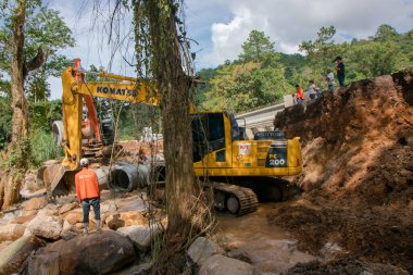 Chiangrai / Tayland - 20 Ağustos 20018, sel sonrası yol rehabilitasyonu. Köylüler uçurumun kenarında duruyorlar ve kazıcının çalışmalarına bakıyorlar, Chiangrai - Chiangmai Yolu 118