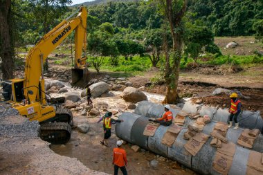 Chiangrai / Tayland - 20 Ağustos 20018, sel sonrası yol rehabilitasyonu, nehirde çalışan sarı kazıcı, Chiangrai - Chiangmai yolu 118
