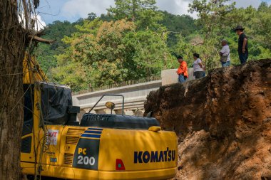 Chiangrai / Tayland - 20 Ağustos 20018, sel sonrası yol rehabilitasyonu. Köylüler uçurumun kenarında duruyorlar ve kazıcının çalışmalarına bakıyorlar, Chiangrai - Chiangmai Yolu 118