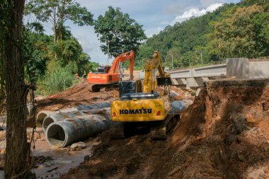 Chiangrai / Tayland - 20 Ağustos 2001, selden sonra yol rehabilitasyonu, turuncu ve sarı kazıcı nehirde çalışıyor, Chiangrai - Chiangmai yolu 118