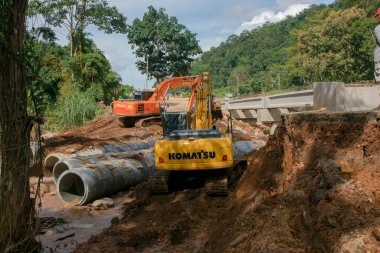 Chiangrai / Tayland - 20 Ağustos 2001, selden sonra yol rehabilitasyonu, turuncu ve sarı kazıcı nehirde çalışıyor, Chiangrai - Chiangmai yolu 118