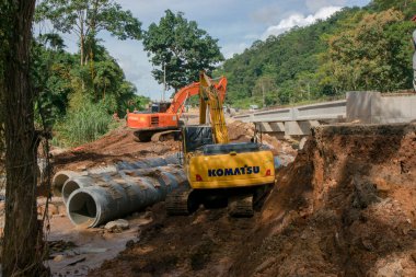 Chiangrai / Tayland - 20 Ağustos 2001, selden sonra yol rehabilitasyonu, turuncu ve sarı kazıcı nehirde çalışıyor, Chiangrai - Chiangmai yolu 118