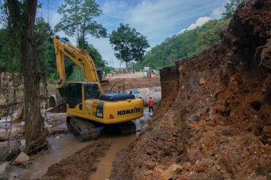Chiangrai / Tayland - 20 Ağustos 20018, sel sonrası yol rehabilitasyonu, nehirde çalışan sarı kazıcı, Chiangrai - Chiangmai yolu 118