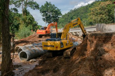 Chiangrai / Tayland - 20 Ağustos 2001, selden sonra yol rehabilitasyonu, turuncu ve sarı kazıcı nehirde çalışıyor, Chiangrai - Chiangmai yolu 118